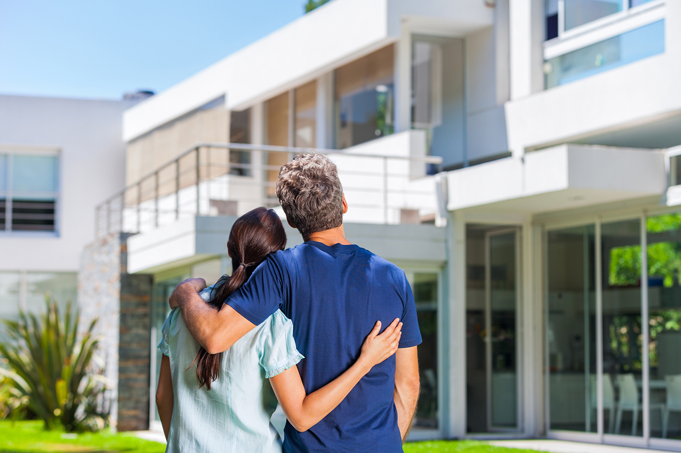 Couple in front of their new house after thorough home inspection services were provided