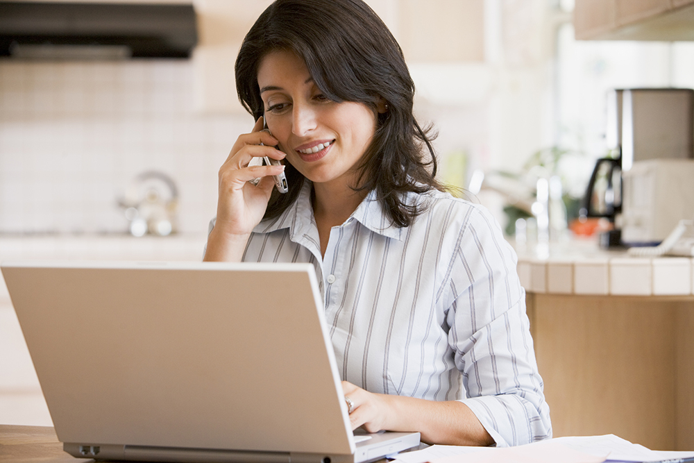 Woman in kitchen with laptop talking on the phone with our home inspectors